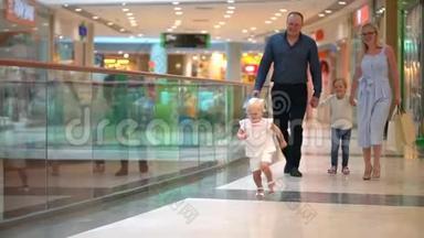 快乐的四口之家在购物。 在商场里的家人。 孩子们在购物中心和父母在一起。 家庭购物在大商店。 家庭